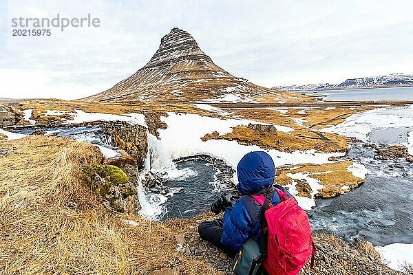Abenteuerlustige Fotografin im Winter in Island beim Fotografieren am Kirkjufell Wasserfall