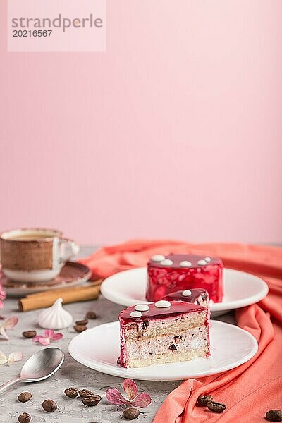 Roter Kuchen mit Soufflé Creme und einer Tasse Kaffee auf grauem und rosa Hintergrund und rotem Stoff. Seitenansicht  Kopierraum