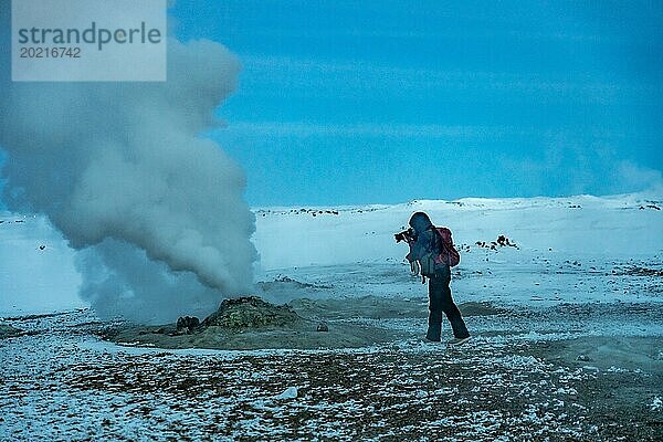 Abenteuerlustige Fotografin im Winter in Island beim Fotografieren im Geothermalgebiet Hverir oder Namafjall