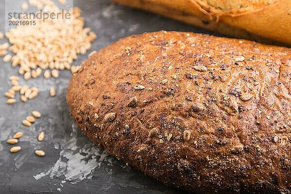 Frisch gebackenes Brot mit Körnern auf einem schwarzen Betonhintergrund. Seitenansicht  selektiver Fokus  Nahaufnahme