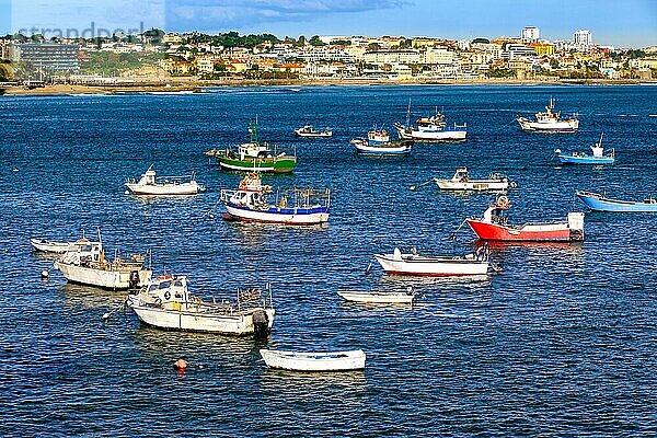 Bunte Ansicht von kleinen Fischerbooten an einem sonnigen Tag in der Bucht von Cascais  Portugal  ruhige und luxuriöse Stadt am Meer in der Nähe von Lissabon mit Stränden und kleinem Hafen. Klarer blauer Himmel  Wolken  Sonnenschein  ruhiges Meerwasser  Häuser an der Küste  Europa