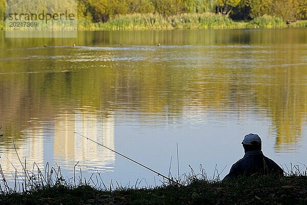 Fischer Silhouette in der Nähe von Teich bei Sonnenuntergang