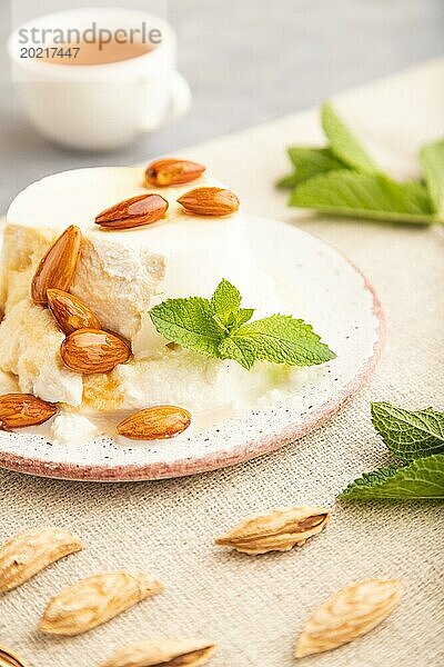 Ricotta Käse mit Honig und Mandeln auf grauem Betonhintergrund und Leinenstoff. Seitenansicht  Nahaufnahme  selektiver Fokus