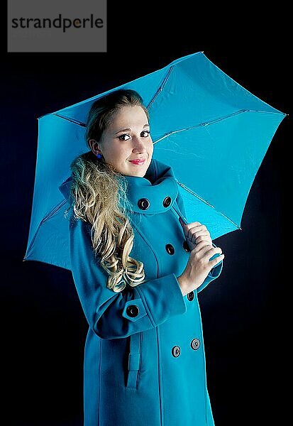 Junges Mädchen im Mantel mit blauem Regenschirm