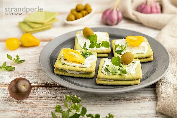 Grüne Cracker Sandwiches mit Frischkäse und Kirschtomaten auf weißem Holzhintergrund und Leinenstoff. Seitenansicht  Nahaufnahme  selektiver Fokus