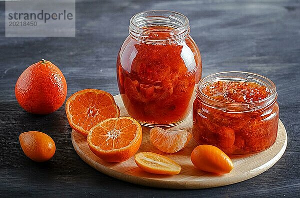 Mandarinen und Kumquatmarmelade in einem Glas mit frischen Früchten auf einem schwarzen Holztisch. Hausgemacht  Kopierraum  Nahaufnahme