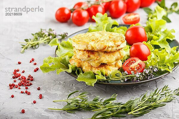 Gehackte Hähnchenschnitzel mit Salat  Tomaten und Kräutern auf einem grauen Betonhintergrund. Seitenansicht  Nahaufnahme  selektiver Fokus