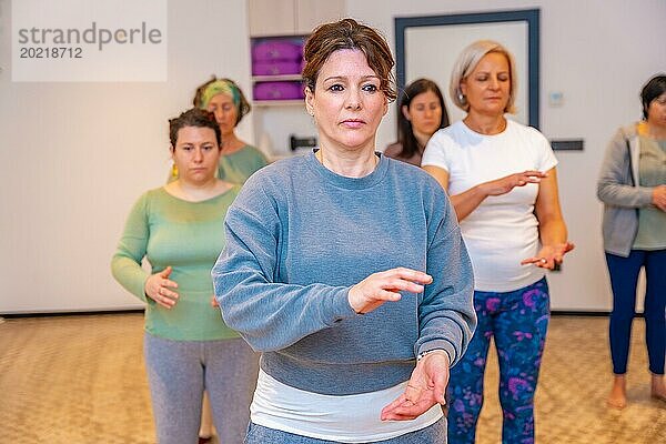 Frontalporträt einer Gruppe erwachsener kaukasischer Frauen in einem Qi Gong Kursraum