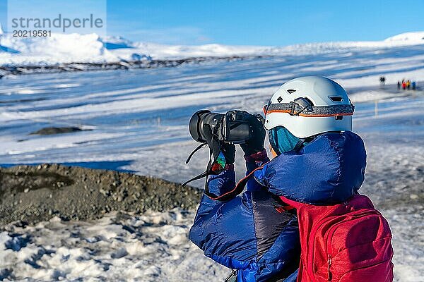 Abenteuerlustige Fotografin im Winter in Island beim Fotografieren auf dem Vatnajokull Gletscher