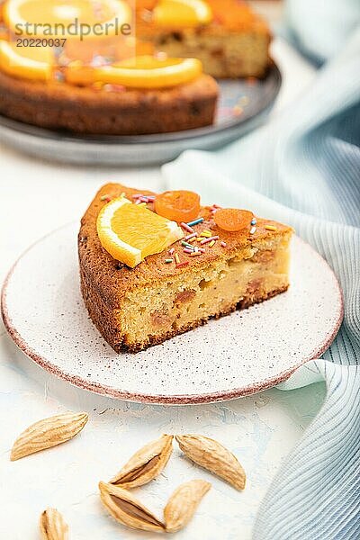 Orangenkuchen mit Mandeln und einer Tasse Kaffee auf einem weißen Betonhintergrund und blauem Leinentuch. Draufsicht  Nahaufnahme  selektiver Fokus