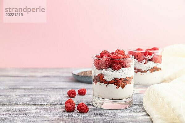 Joghurt mit Himbeeren  Goji Beeren und Chia Samen im Glas auf grauem und rosa Hintergrund und Leinenstoff. Seitenansicht  Kopierraum  selektiver Fokus