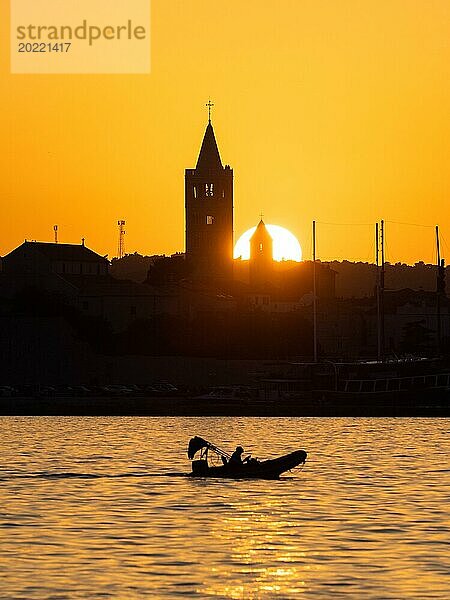 Motorboot im goldenen Abendlicht bei Sonnenuntergang  Silhouette der Kirchtürme von Rab  Stadt Rab  Insel Rab  Kvarner Bucht  Kroatien  Europa