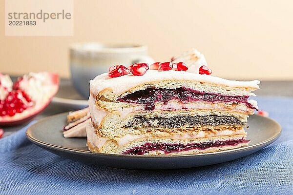 Hausgemachter Schichtkuchen mit Granatapfelmarmelade und einer Tasse Kaffee auf einem schwarzen Betonhintergrund und blauem Textil. Seitenansicht  Nahaufnahme  selektiver Fokus