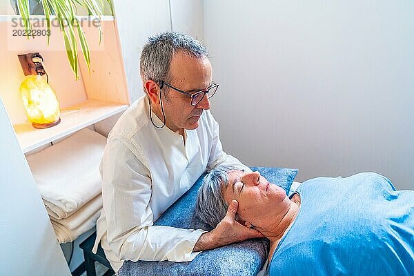 Älterer männlicher Therapeut bei einer orientalischen Nackenmassage an einer reifen Frau in einer Klinik