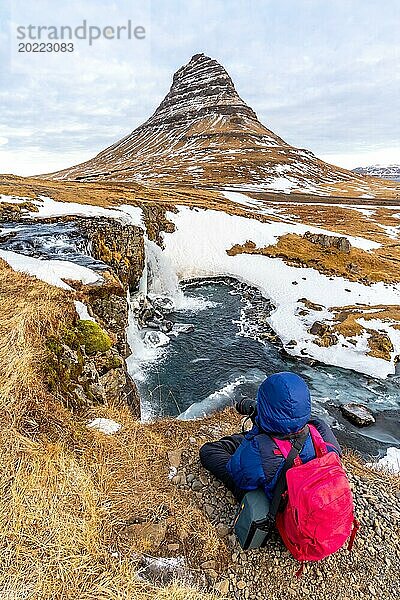 Abenteuerlustige Fotografin im Winter in Island beim Fotografieren am Kirkjufell Wasserfall und seinem schönen Berg