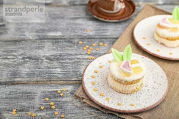 Dekorierter Kuchen mit Milch und Kokosnusscreme mit einer Tasse Kaffee auf einem grauen Holzhintergrund und Leinenstoff. Seitenansicht  Nahaufnahme  selektiver Fokus