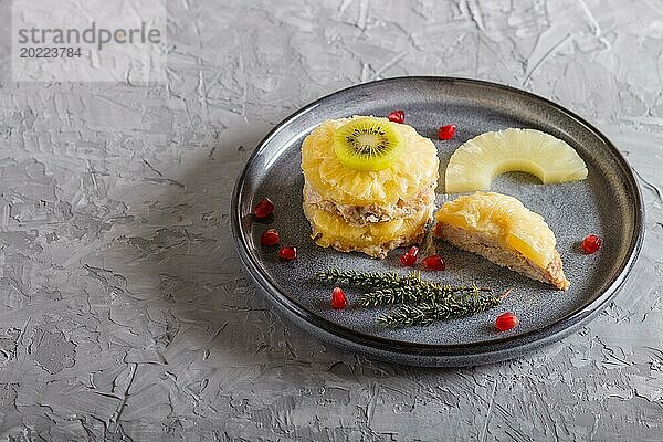 Stücke von gebackenem Schweinefleisch mit Ananas  Käse und Kiwi auf grauem Teller  Seitenansicht  Nahaufnahme  selektiver Fokus  Kopierraum