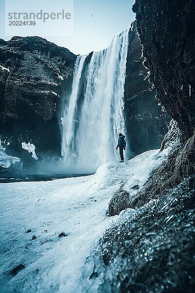 Silhouette einer Frau im Winter in Island unter dem Skogafoss Wasserfall bei Temperaturen von 20 Grad unter Null. Mit dem Boden gefroren mit Eis