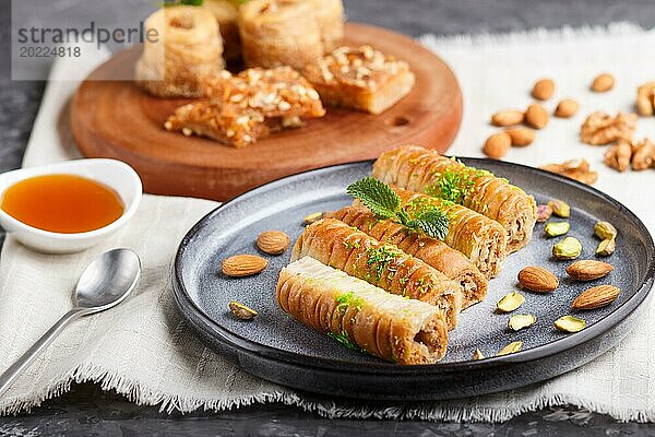 Set verschiedener traditioneller arabischer Süßigkeiten: Baklava  Kunafa  Basbus in Keramiktellern auf grauem Betonhintergrund. Seitenansicht  selektiver Fokus