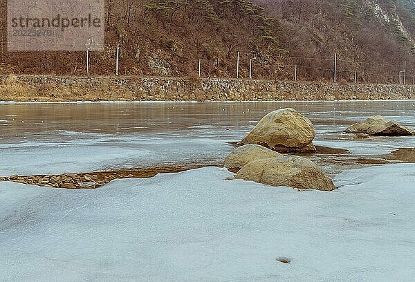 Friedliche gefrorene Flussszene mit Felsen in einer ruhigen Winterdämmerung in Südkorea