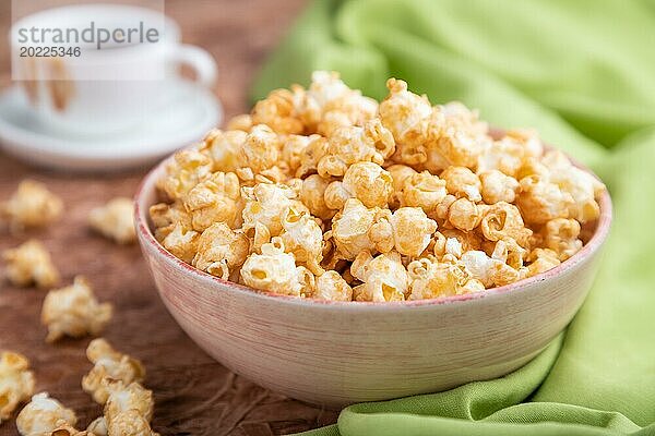 Popcorn mit Karamell in einer Keramikschale auf braunem Betonhintergrund und grünem Textil. Seitenansicht  Nahaufnahme  selektiver Fokus