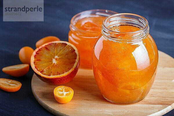 Orangen und Kumquatmarmelade in einem Glas mit frischen Früchten auf einem Küchenbrett aus Holz. Hausgemacht  Nahaufnahme