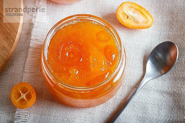 Orangen und Kumquatmarmelade in einem Glas mit frischen Früchten auf einer weißen Leinentischdecke. Hausgemacht  Nahaufnahme