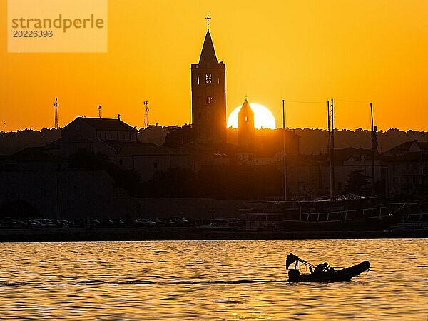 Motorboot im goldenen Abendlicht bei Sonnenuntergang  Silhouette der Kirchtürme von Rab  Stadt Rab  Insel Rab  Kvarner Bucht  Kroatien  Europa