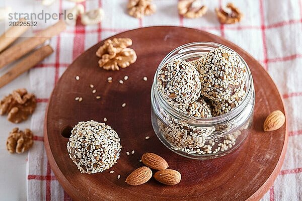 Energiekugeln mit Mandeln  Sesam  Cashew  Walnüssen  Datteln und gekeimtem Weizen auf Holzbrett in Glasgefäß  Seitenansicht  Nahaufnahme