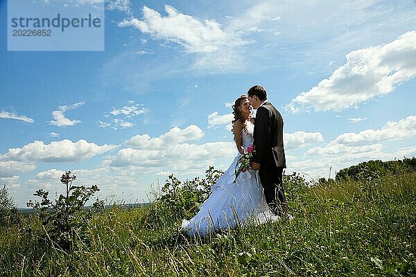 Hochzeitspaar stehen im Gras in sonnigen Sommertag