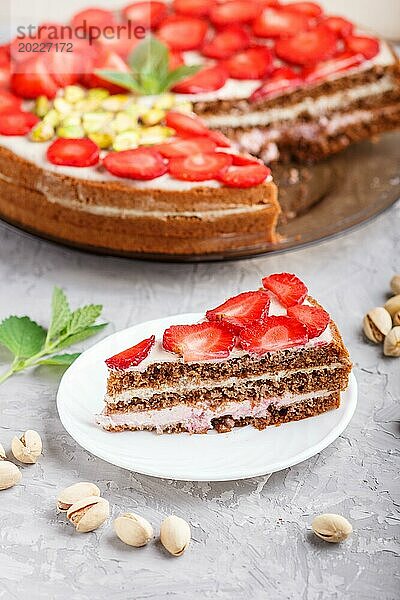 Hausgemachter Kuchen mit Joghurtcreme  Erdbeeren  Pistazien und einer Tasse Kaffee auf einem grauen Betonhintergrund. Seitenansicht  selektiver Fokus  Nahaufnahme