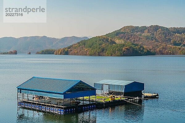 Ein schwimmendes Gebäude mit blauem Dach auf einem ruhigen See mit Bergen in der Ferne  in Südkorea