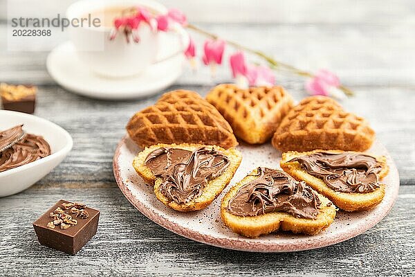 Hausgemachte Waffel mit Schokoladenbutter und Tasse Kaffee auf einem grauen Holzhintergrund. Seitenansicht  selektiver Fokus  Nahaufnahme