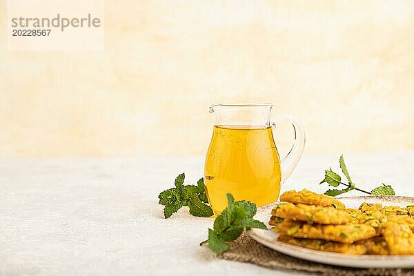 Traditionelles iranisches Dessert Sohan mit einem Glas grünem Tee auf einem grauen Betonhintergrund und Leinentextil. Seitenansicht  Nahaufnahme  selektiver Fokus  Kopierraum