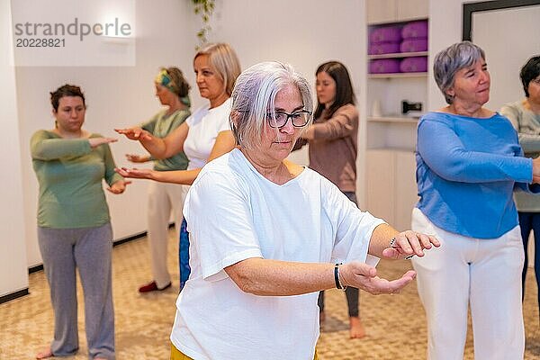 Reife  erwachsene  kaukasische  konzentrierte Frauen  die während eines Qi Gong Kurses zu zweit üben