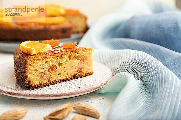 Orangenkuchen mit Mandeln und einer Tasse Kaffee auf einem weißen Betonhintergrund und blauem Leinentuch. Draufsicht  Nahaufnahme  selektiver Fokus