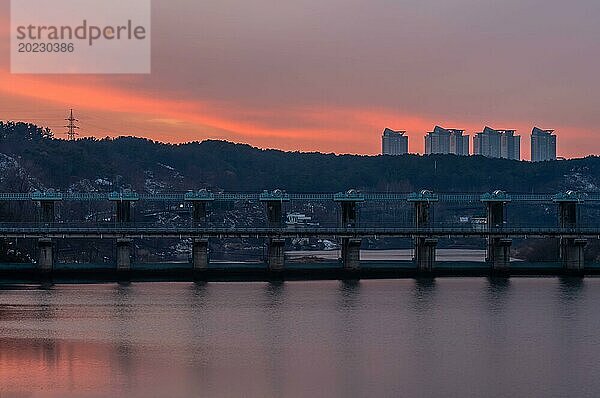 Heitere Dämmerung über einem Fluss mit Staudamm und gespiegelter Stadtlandschaft  in Südkorea