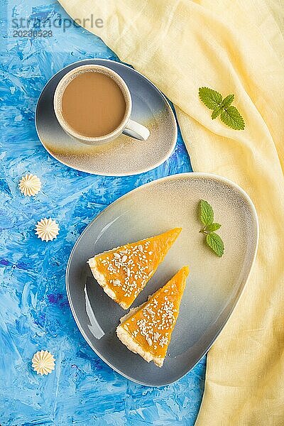 Zwei Stücke traditioneller amerikanischer Kürbiskuchen mit einer Tasse Kaffee auf einem blauen Betonhintergrund und gelbem Stoff. Draufsicht  Flachlage  Nahaufnahme  Kontrast