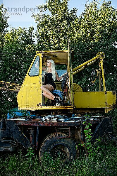 Schöne junge Frau sitzt im Traktor im Sommer