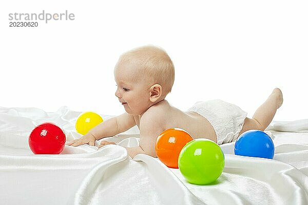 Nettes Baby spielen im Bett mit Farbe Bälle isoliert