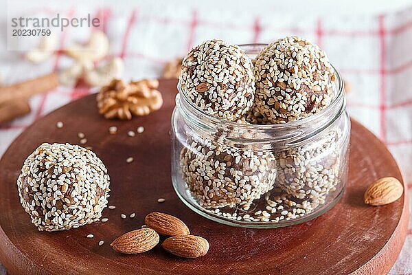 Energiekugeln mit Mandeln  Sesam  Cashew  Walnüssen  Datteln und gekeimtem Weizen auf Holzbrett in Glasgefäß  Seitenansicht  Nahaufnahme