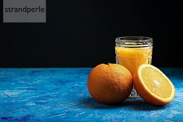 Glas Orangensaft auf einem schwarzen und blauen Hintergrund. Hartes Licht  Kontrast. Seitenansicht  Kopierraum