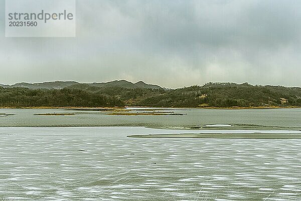 Ruhige  aber trostlose Winterlandschaft mit einem von Eis bedeckten Fluss  umgeben von Hügeln  in Südkorea