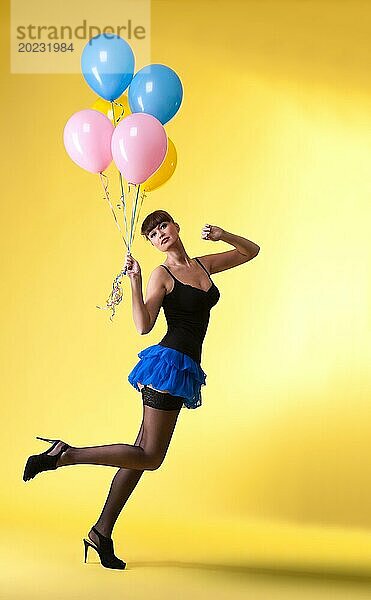 Hübsche Frau mit Luftballons Pinup Stil auf gelb