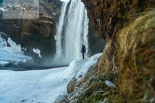 Silhouette einer Frau im Winter in Island unter dem Skogafoss Wasserfall bei Temperaturen von 20 Grad unter Null. Mit dem Boden gefroren mit Eis