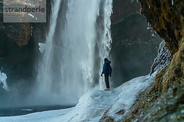 Silhouette einer Frau im Winter in Island beim Besuch des Wasserfalls Skogafoss