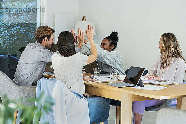 Coworkers high fiving after finished project at office