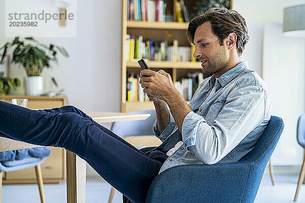 Relaxed businessman working at home sitting on chair with feet on table