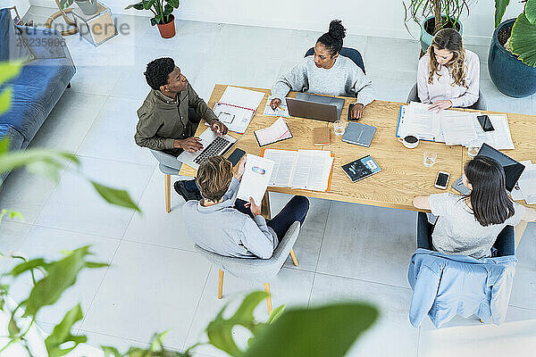Blick aus der Vogelperspektive auf im Büro versammelte Geschäftsleute  die über Arbeit diskutieren