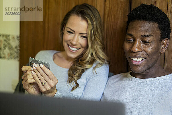 Glückliches Paar kauft online am Laptop ein  während es im Bett liegt